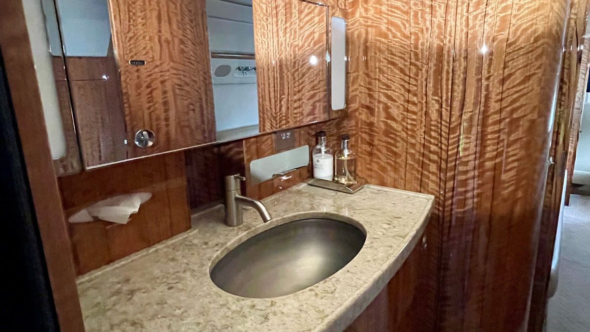 bathroom interior of a private jet furnitured with a mirror and sink as well as stone and wood accents