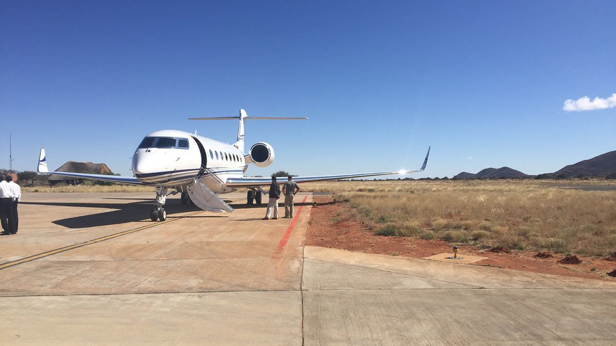 two man standing on the airstrip beside a private jet in the desert