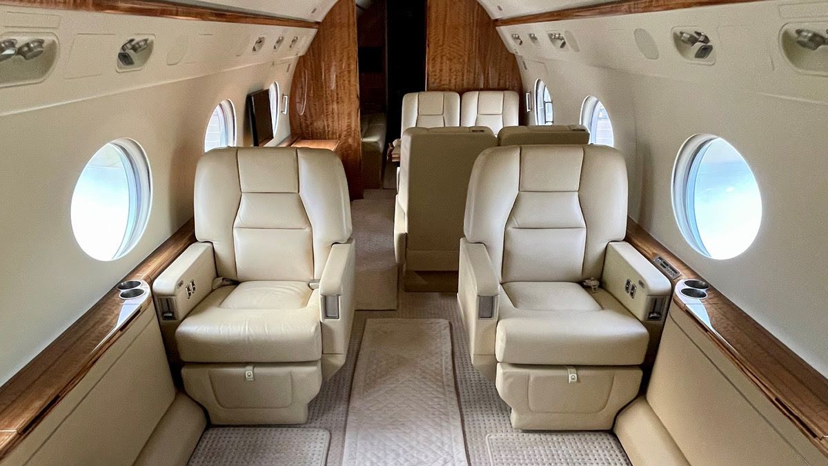 bright interior of a private jet with cream seats and glossy wood accents