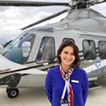 a member of the sales team stands smiling before a silver helicopter